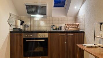 A kitchen with a built-in oven, a window above the sink, and a skylight.