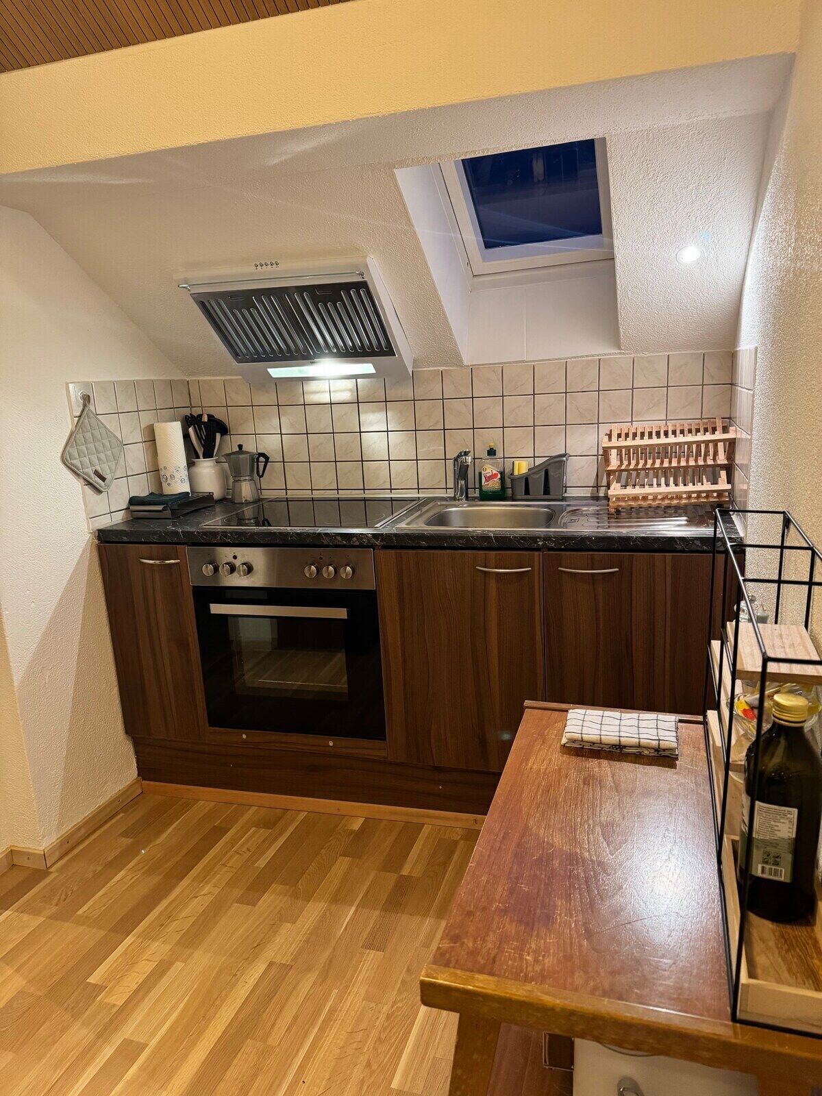 A compact kitchen with a built-in oven, a wooden countertop, and a small dining table.