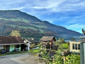 Un pueblo rural con casas tradicionales, un patio empedrado y montañas al fondo.