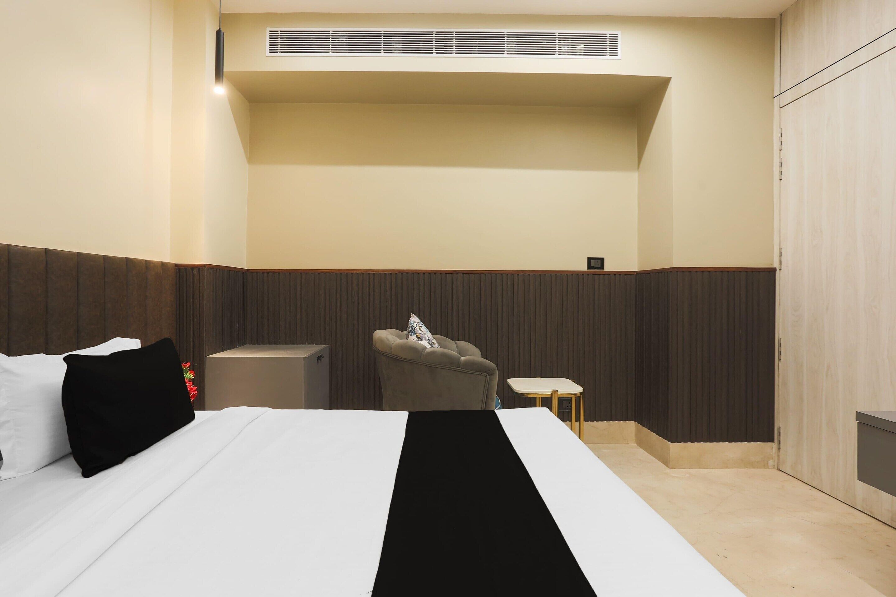 Una habitación de hotel con cama, una silla, una mesita y un armario.
