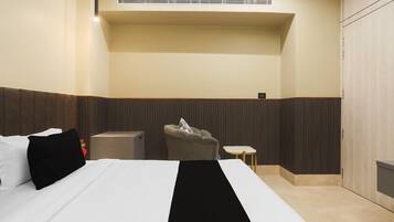 Una habitación de hotel con cama, una silla, una mesita y un armario.
