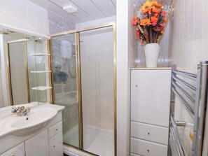 A bathroom with a glass shower enclosure, a white sink, and a cabinet with drawers. - 1 Hilton Flats (Tenby)