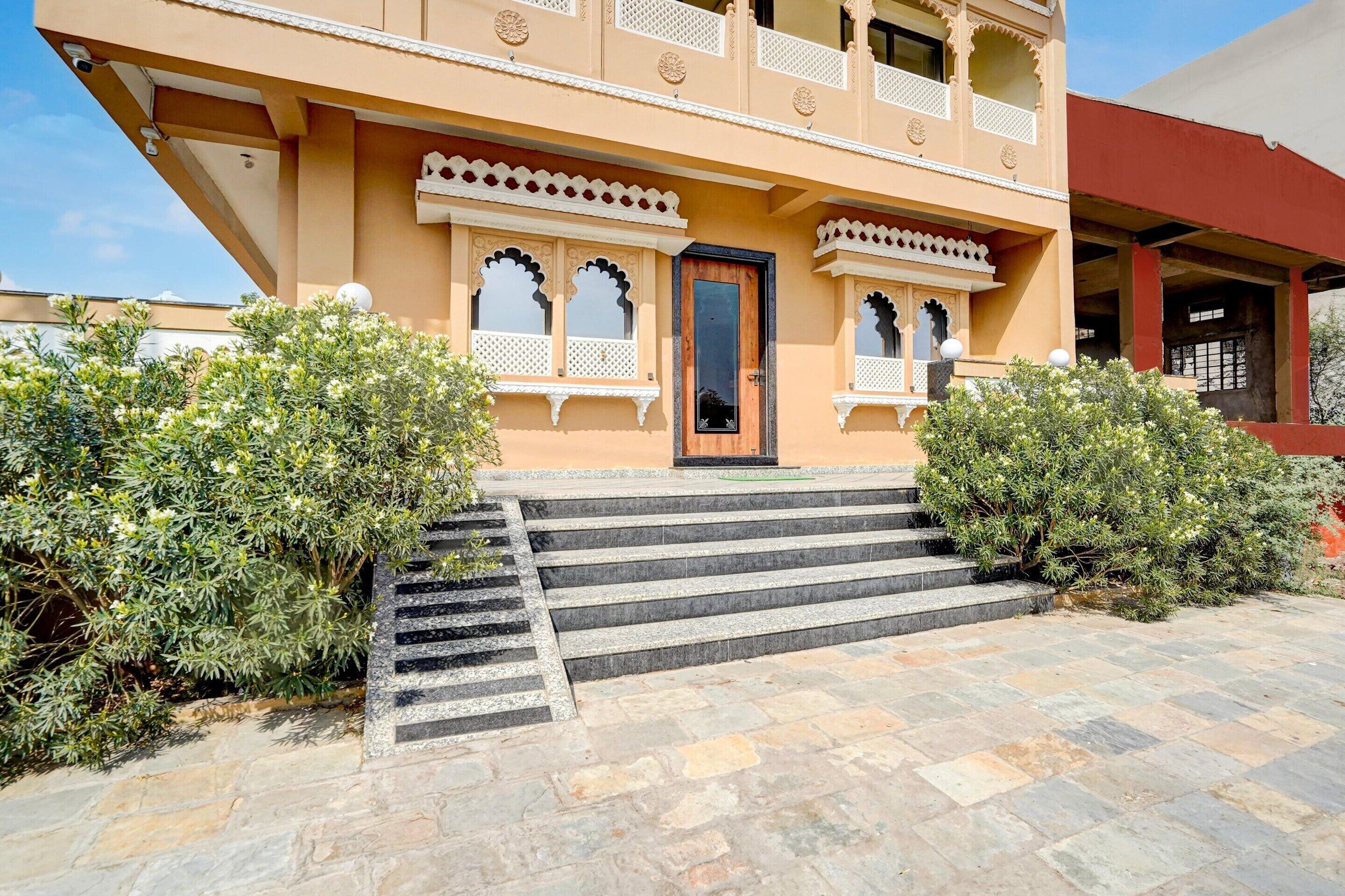 A multi-story building with a traditional architectural style, featuring a central entrance with steps, decorative balconies, and a flat roof.