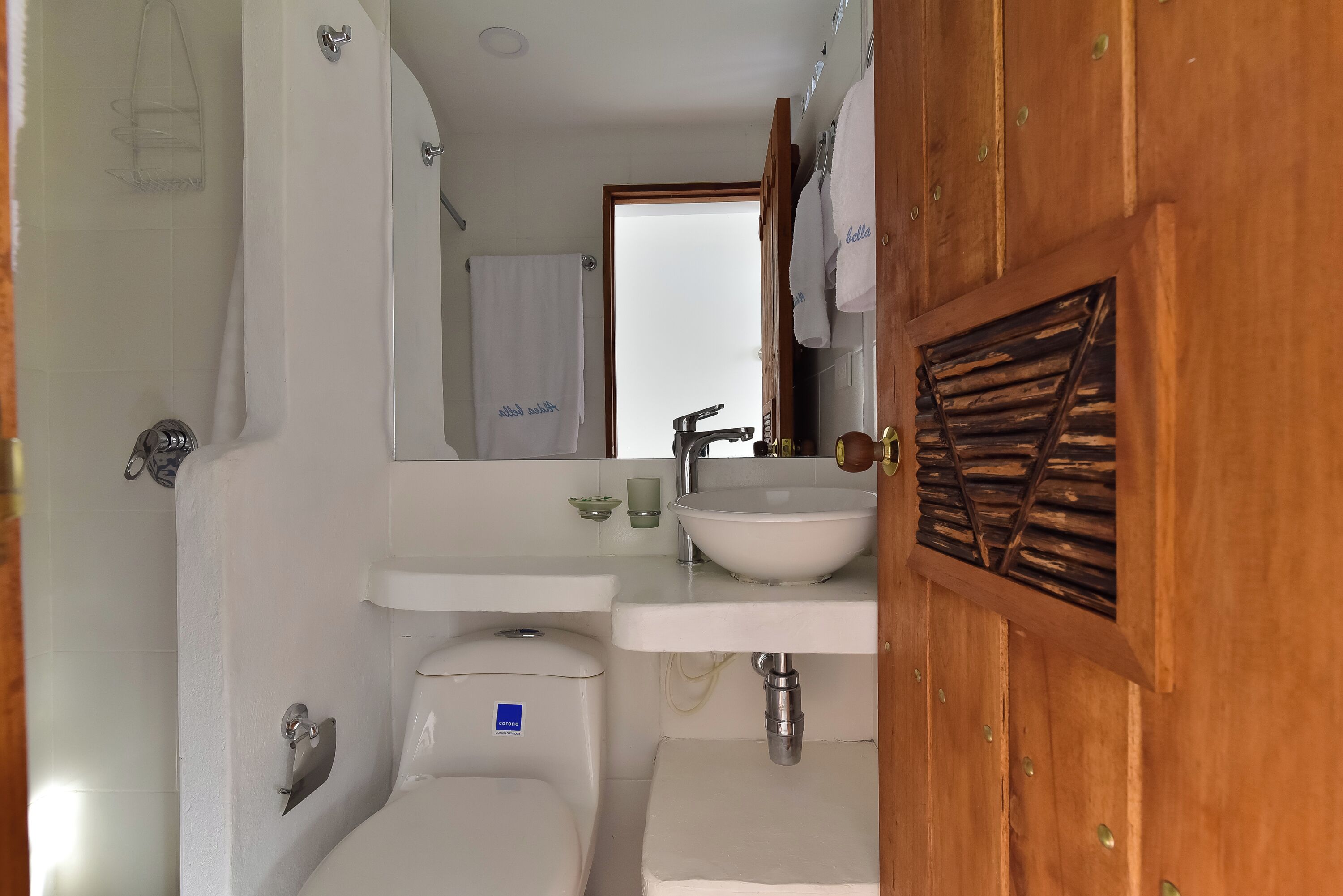 Un baño con lavamanos blanco, espejo, inodoro y cortina de ducha.