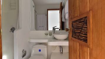 Un baño con lavamanos blanco, espejo, inodoro y cortina de ducha.