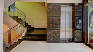 A modern interior with a staircase, elevator, and a glass door leading to a balcony. - Deluxe Hotel Kapil Residency (Pune)