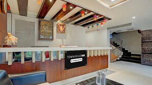 A reception desk with a sign reading 'TOWNHOUSE OAK,' a statue, framed artwork, and a staircase leading to an upper level. - Deluxe Hotel Kapil Residency (Pune)