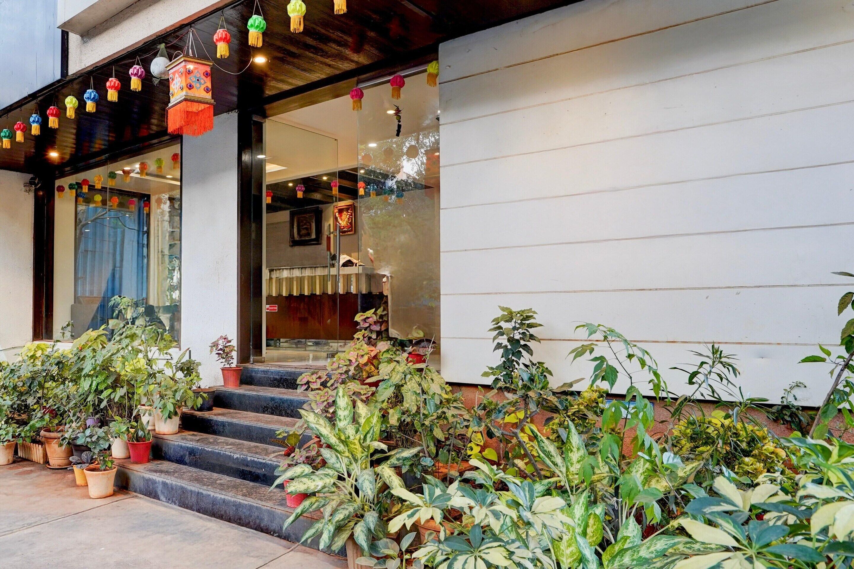 A building entrance with steps leading up to a door, surrounded by potted plants.