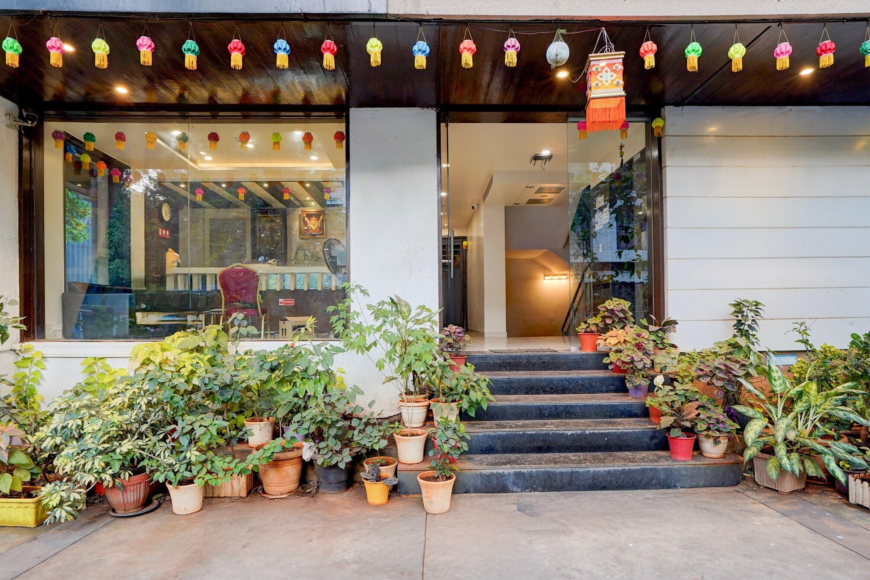 A building entrance with steps leading up to a door, surrounded by potted plants.