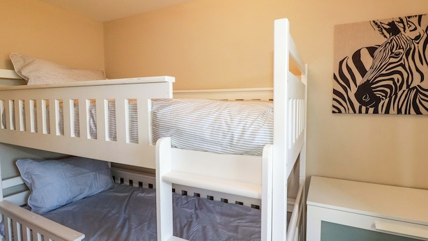 Habitación infantil con literas, un cuadro de cebra y una mesita de noche pequeña.