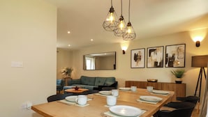 Un comedor con una mesa de madera dispuesta para cuatro personas, sillas negras, un espejo y cuadros en la pared.