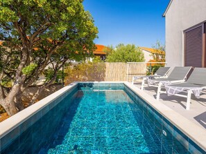 A rectangular swimming pool with clear blue water, surrounded by a wooden fence, and adjacent to a building with a white exterior. - Villa Mila Near Beaches & Center (Supetar)