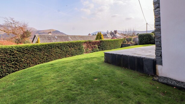 A well-maintained lawn, a stone wall, and a building with a stone facade. - Lakes View (Keswick)