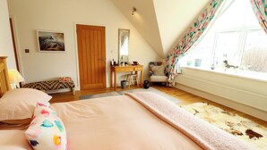 A bedroom with a bed, a desk, a chair, a window with curtains, and a radiator. - Lakes View (Keswick)