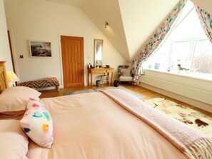 Ein Schlafzimmer mit Bett, Schreibtisch, Stuhl, einem Fenster mit Vorhängen und einer Heizung.