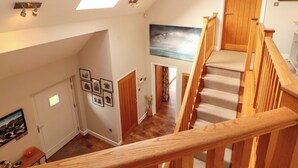 A staircase with wooden railings leading to a landing, a skylight, and a painting on the wall. - Lakes View (Keswick)