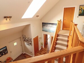 Eine Treppe mit Holzbalkonen, die zu einer Zwischenebene führt, mit einem Oberlicht und einem Gemälde an der Wand.
