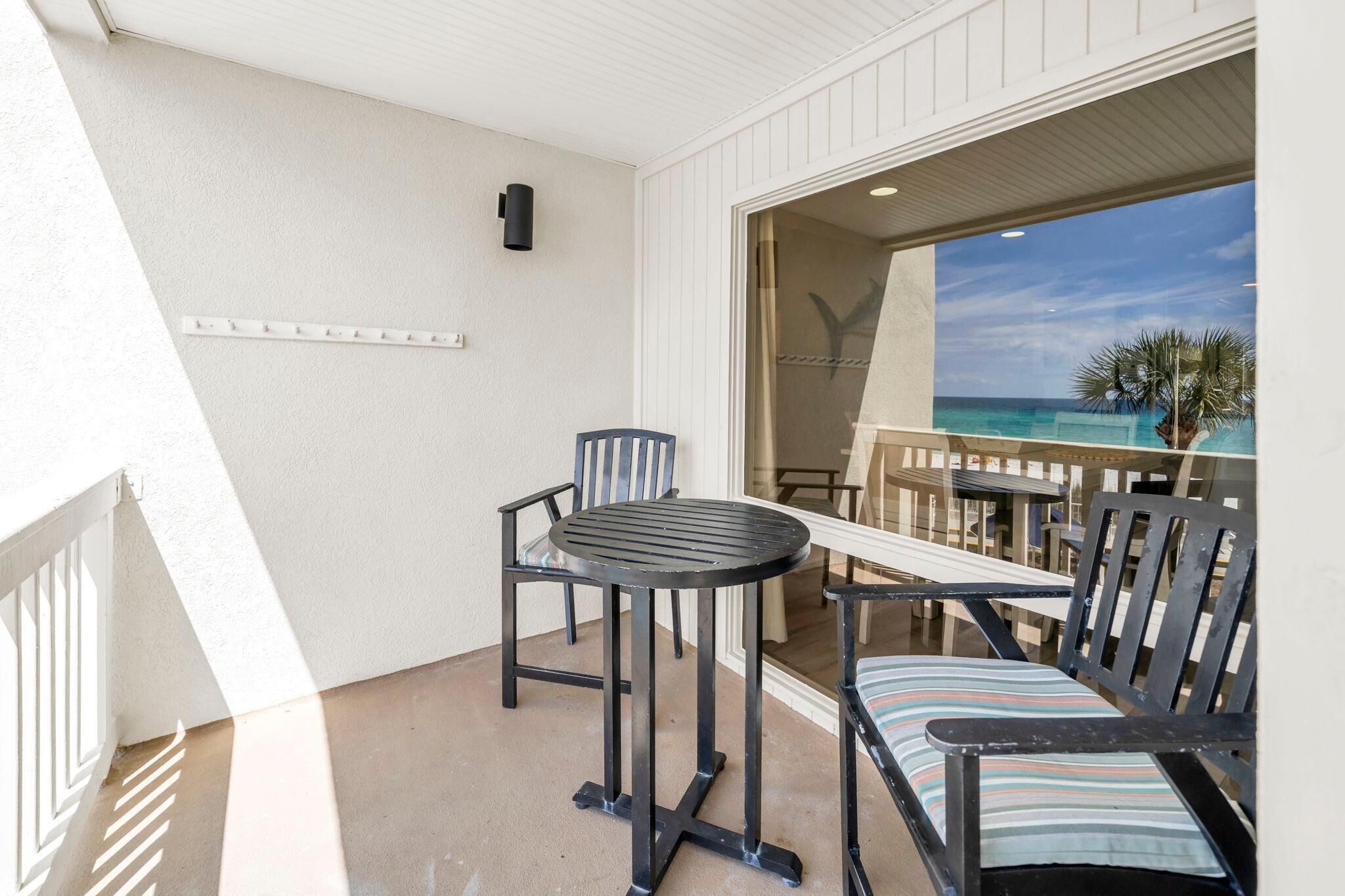 Un balcon avec une table et des chaises, une vue sur l’océan et un palmier.