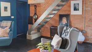 Una stanza con una porta blu, una scala, un divano, una sedia e un muro decorato con quadri.