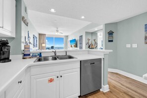 A modern kitchen with a stainless steel sink, white cabinetry, and a dishwasher. - Majestic Beach Towers 2-1704 (Panama City Beach)