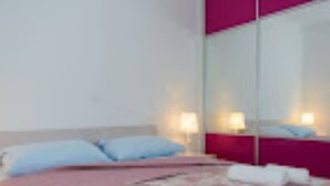 Une chambre d’hôtel avec un lit, des oreillers, une table de chevet avec une lampe et un grand miroir.