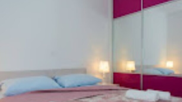 Une chambre d’hôtel avec un lit, des oreillers, une table de chevet et un miroir.