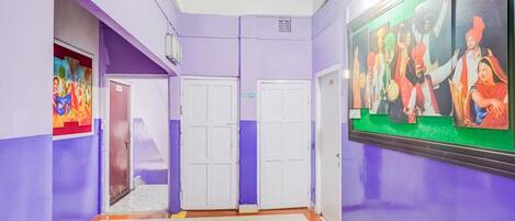 A hallway with purple walls, white doors, and a ceiling fan.