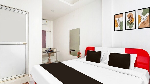 A modern hotel room with a bed, a desk, a mirror, and artwork on the wall.