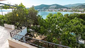 A balcony with a view of a lake, surrounded by greenery and hills. - Blue Magic Apartment (Seget)