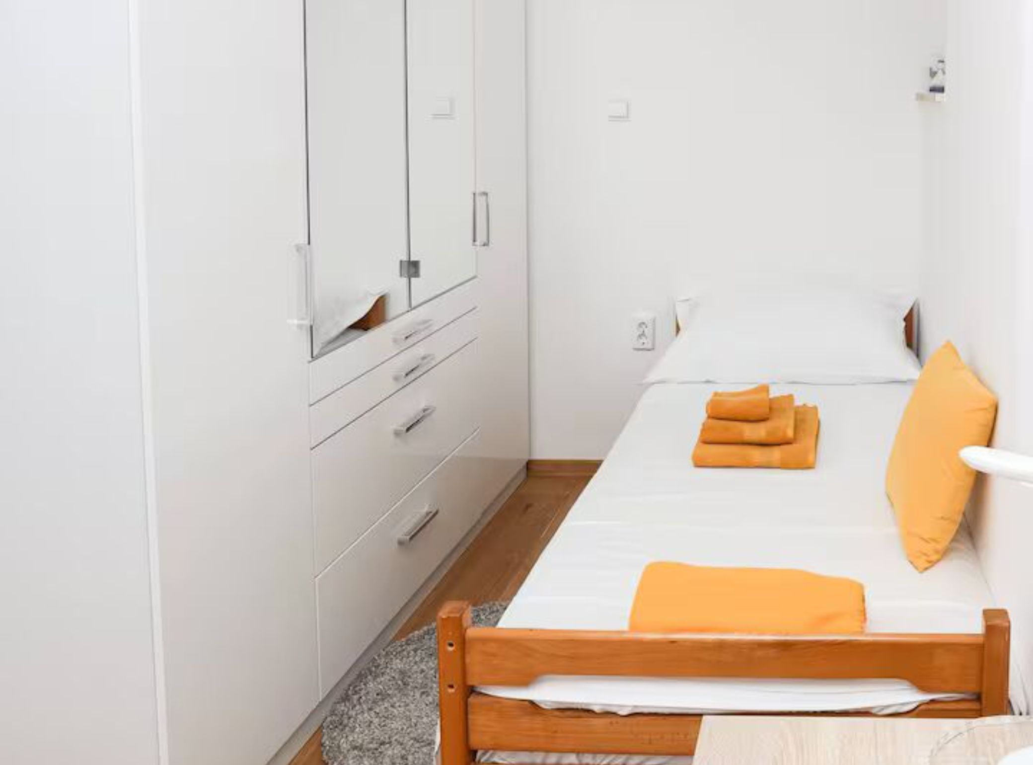 Une chambre à coucher avec un lit en bois, une literie blanche et un miroir au-dessus d’une commode.
