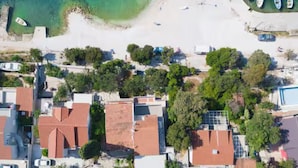 An aerial view of a coastal area with buildings, a beach, and boats. - Blue Magic Apartment (Seget)