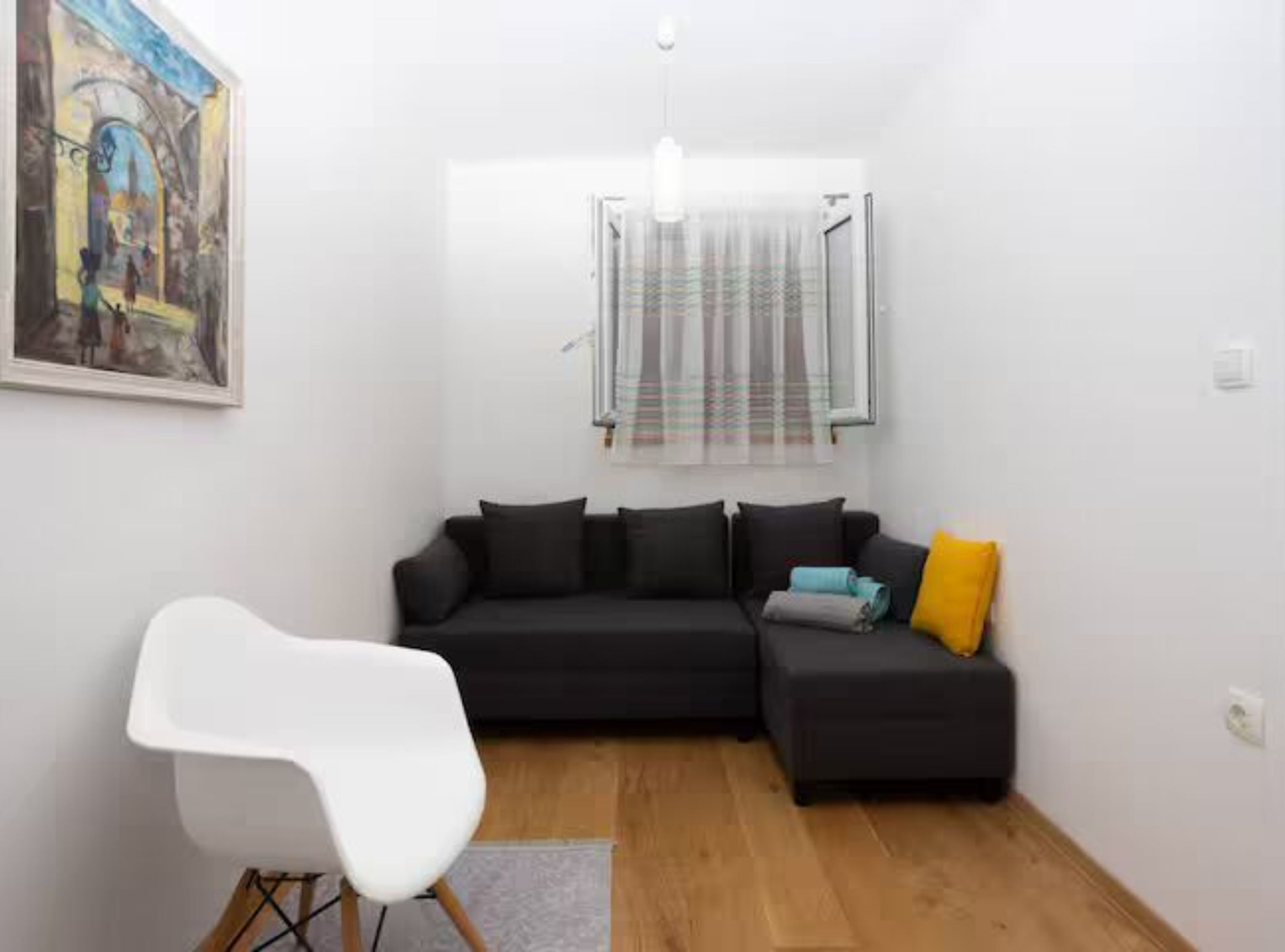 Ein modernes Wohnzimmer mit einem Ecksofa, einem weißen Sessel und einem Gemälde an der Wand.
