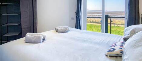 Un dormitorio con cama, dos toallas, una ventana con vistas y un armario.