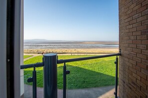 A balcony with a view of a beach and distant mountains.