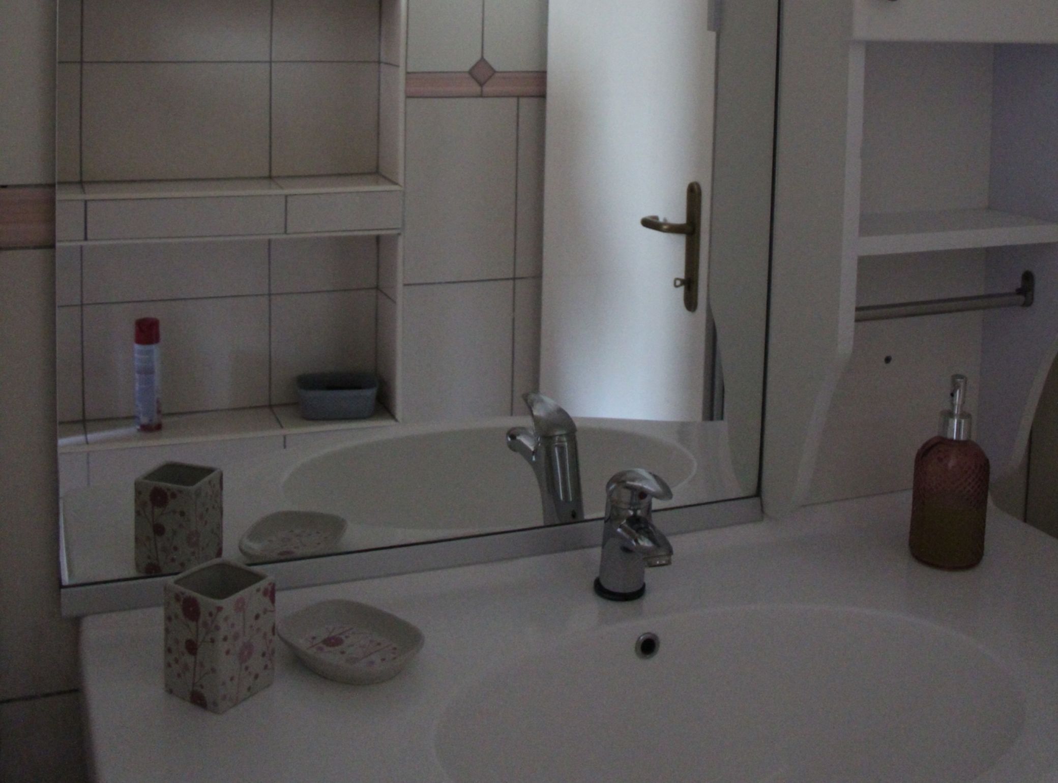 Een badkamer met een wit wastafel, een spiegel, een badkuip en een toilet.