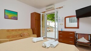 A hotel room with a bed, a wooden wardrobe, a television, and a view through a glass door. - Villa Azure Saplunara (Mljet)