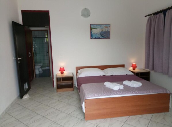 A bedroom with a bed, two bedside tables with lamps, a door, a painting on the wall, and a curtain. - Villa Azure Saplunara (Mljet)