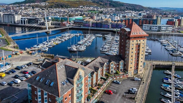 A marina with boats, a bridge, and buildings with balconies. - The Crows Nest - 1 Bed Apartment - Swansea Marina (Swansea)