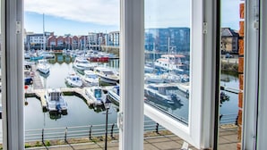 A marina with boats docked, a clear sky, and buildings in the background. - The Crows Nest - 1 Bed Apartment - Swansea Marina (Swansea)