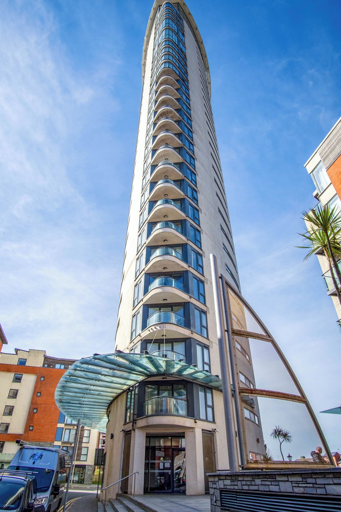 Un grand hôtel moderne à la façade incurvée, doté d’une entrée en verre et offrant une vue sur un ciel dégagé.