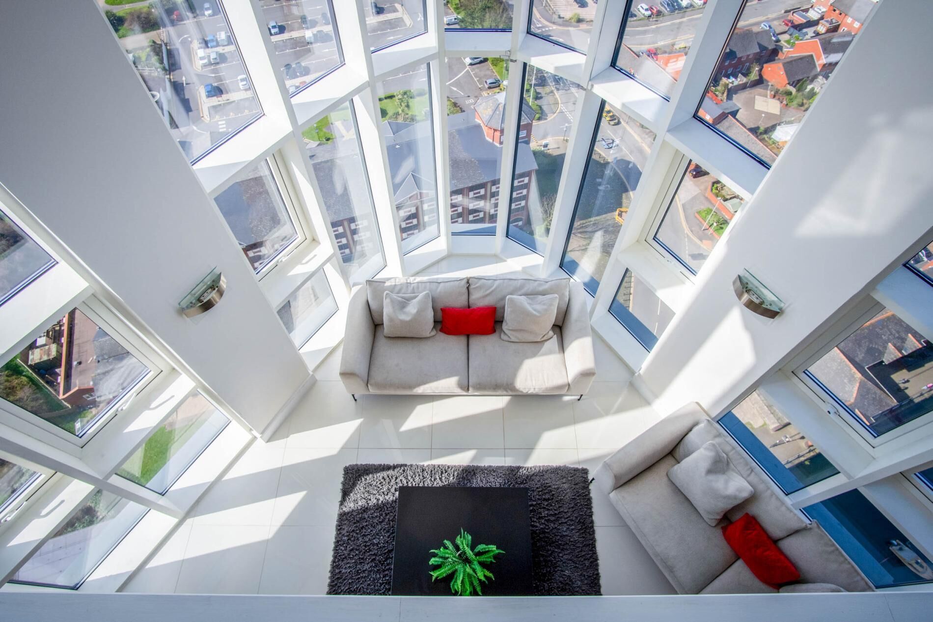 Interior de un edificio alto con una zona de estar central, amplias ventanas y vistas a la ciudad.