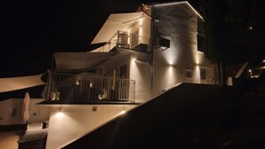 A modern multi-story building with a prominent staircase, balconies, and exterior lighting. - Sanktvid Residence (Hodilje)
