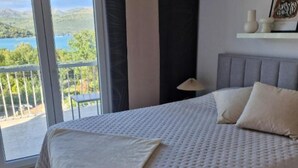 A bedroom with a large bed, a view of a lake, and a balcony. - Sanktvid Residence (Hodilje)