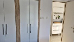 A bedroom with a bed, a wardrobe, and a kitchenette area. - Sanktvid Residence (Hodilje)