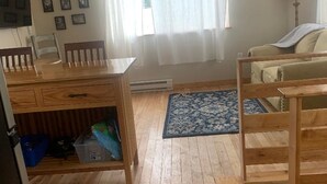 Une pièce comprenant une table à manger, des chaises, un canapé, un tapis à motifs et une fenêtre avec des rideaux.