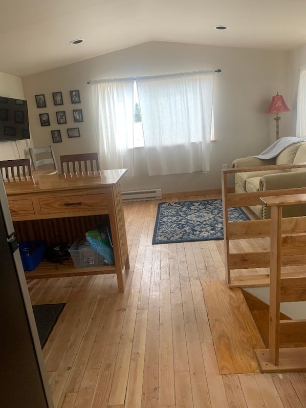 A room with a dining table, chairs, a sofa, a patterned rug, and a window with curtains. - Adorable 1-bedroom upstairs apartment in charming Parker for a relaxing stay! (Parker)