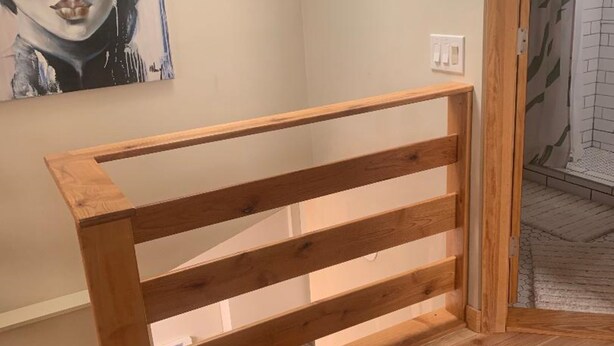 Un banc en bois dans une pièce dont le sol est carrelé, un tableau accroché au mur et un espace douche visible à travers une porte.