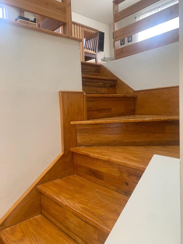 A wooden staircase with a handrail and a chair at the top.