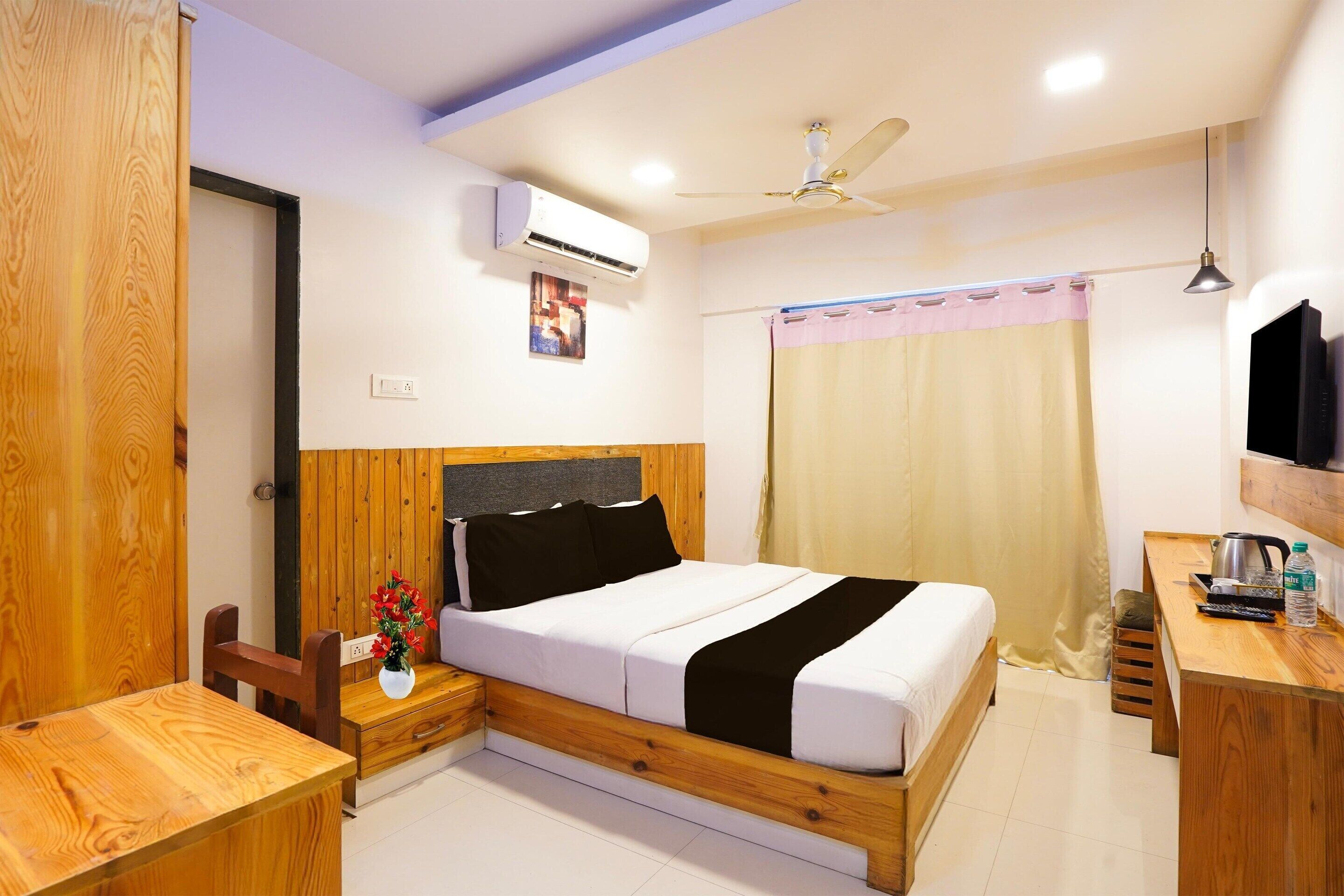Une chambre à coucher avec un lit en bois, des tables de chevet, un bureau, un ventilateur de plafond et un appareil de climatisation.