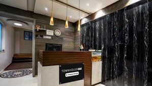 Un taulell de recepció amb un cartell que diu 'Townhouse Oak', un rellotge i una paret amb dibuixos de marbre negre.